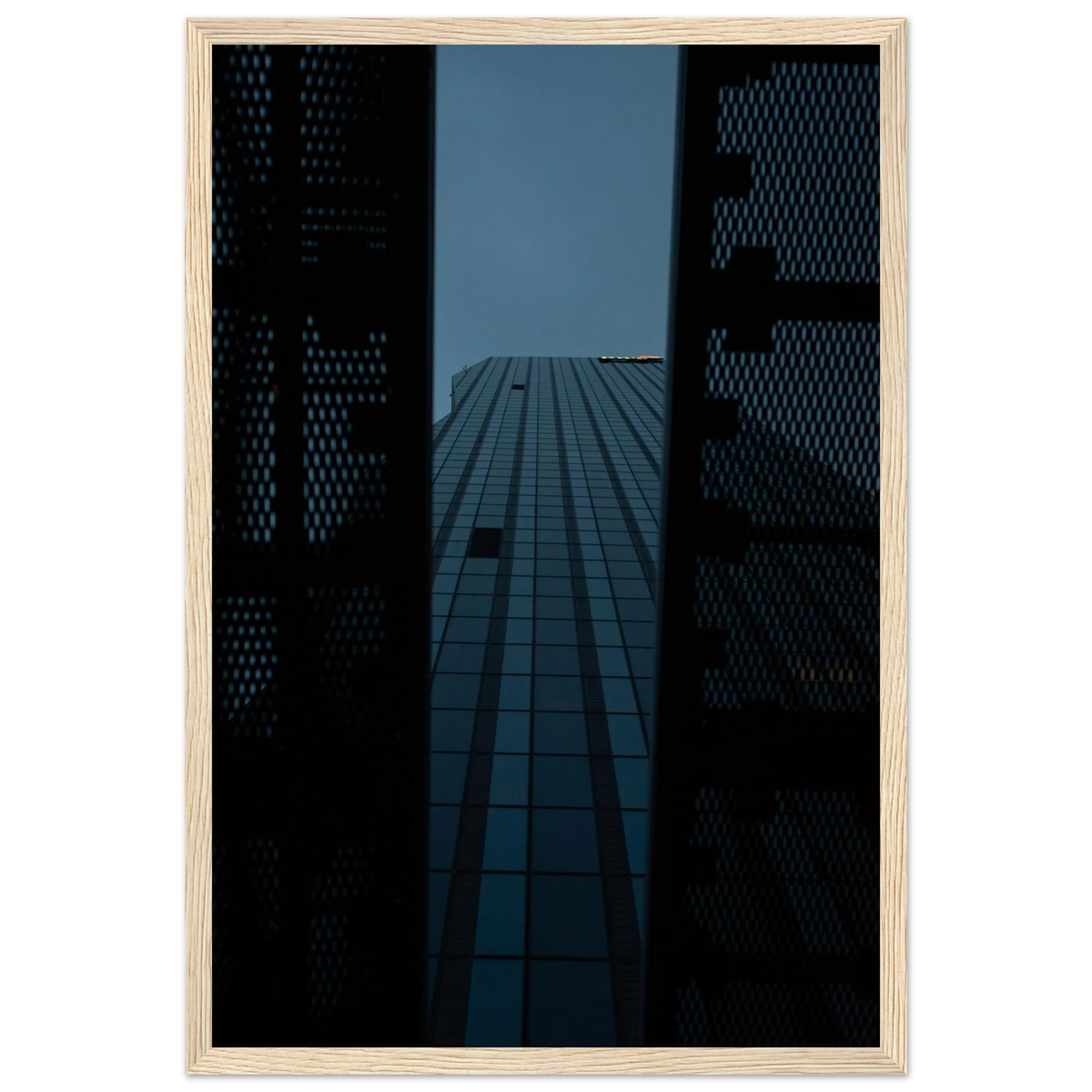 Low angle view looking up at a tall glass skyscraper framed between two metal structural elements on wooden framed wall art