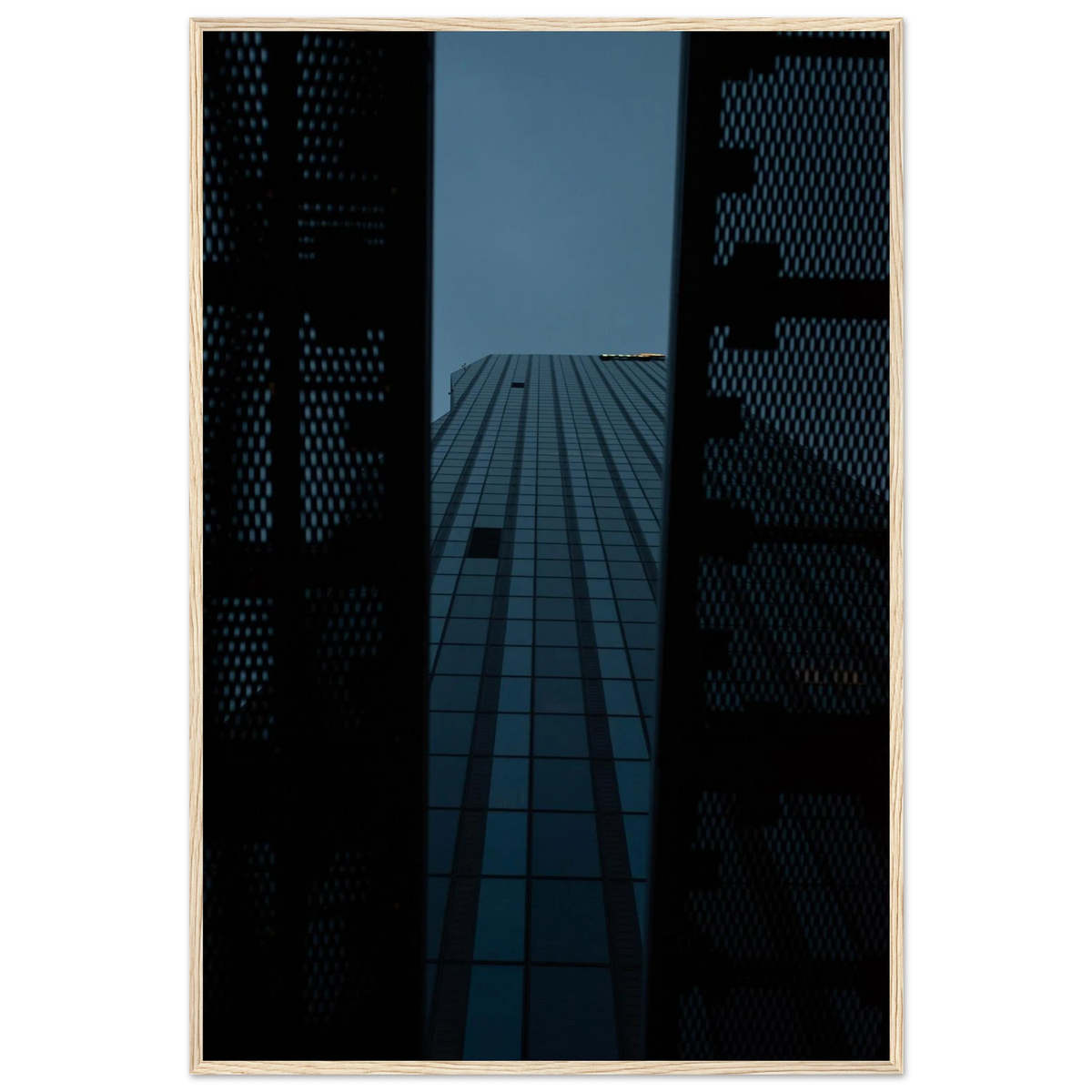 Low angle view looking up at a tall glass skyscraper framed between two metal structural elements on wooden framed wall art