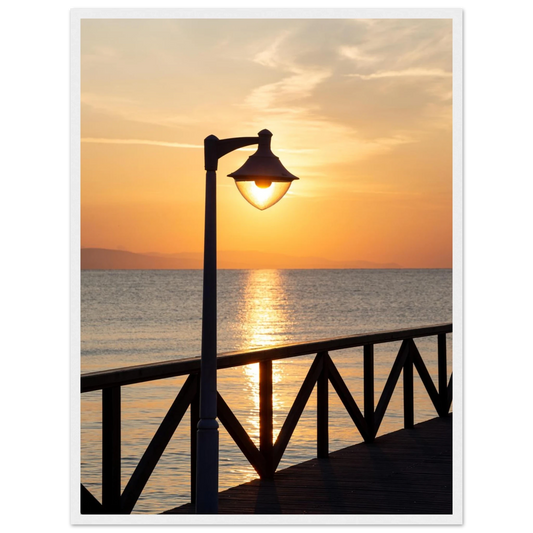 Wooden framed wall art of a sunset over the sea with a street lamp on the pier